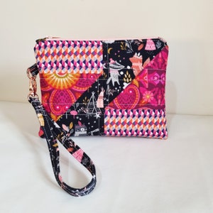 May include: A pink, black and white patchwork fabric zipped pouch with a black strap. The pouch has a geometric pattern and features a variety of animal and nature-inspired designs.