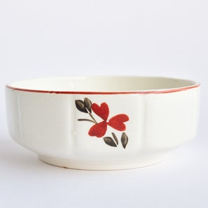 May include: White ceramic bowl with a red floral design and a red rim. The bowl has a fluted design.