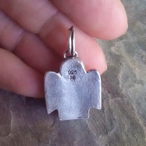 the back of an angel pendant showing the maker mark and metal quality stamp