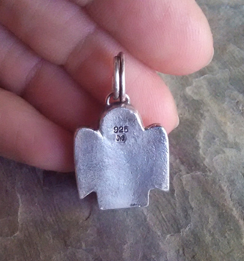 the back of an angel pendant showing the maker mark and metal quality stamp