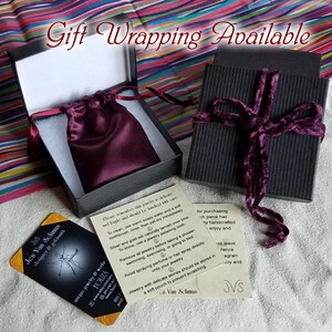 gift wrapping for Etsy shop Fouza showing small decorative pouch within cotton lined black striped box, maroon velvet ties, and colorful stripped tissue paper