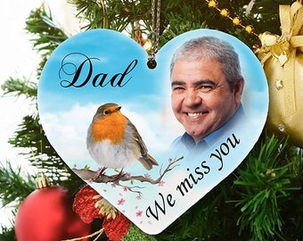 May include: A blue heart-shaped Christmas ornament with a photo of a man and a robin on a branch. The ornament says "Dad" and "We miss you".