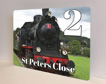 May include: A rectangular sign featuring a black and red steam train on a green field with a cloudy sky background. The number "2" is in the upper right corner. The text "St Peters Close" is at the bottom.