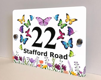 May include: White rectangular house number sign with the number "22" in black. The sign is decorated with colorful butterflies and a floral border. The text "Stafford Road" is below the number.