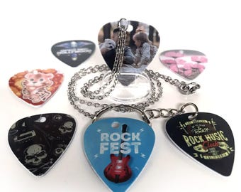 May include: A collection of guitar picks with various designs, including a photo pendant and picks with skull, tiger, and floral graphics. One pick features a red guitar and the text "ROCK FEST". A silver chain necklace is also included.