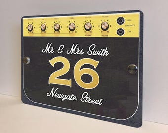 May include: A black and gold house sign with the text "Mr & Mrs Swith 26 Newgate Street". The sign has a design resembling an amplifier, with knobs and the words "High" and "Low".