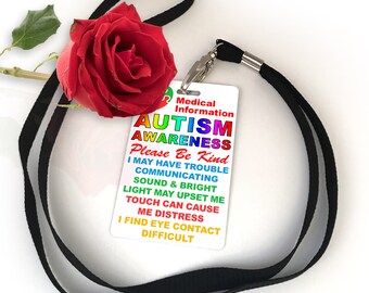 May include: A white card with the words "Medical Information Autism Awareness Please Be Kind" in rainbow colors. The card also includes the text "I may have trouble communicating, sound & bright light may upset me, touch can cause me distress, I find eye contact difficult". The card is attached to a black lanyard.
