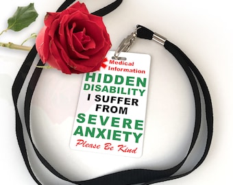 May include: A white card with red and green text that reads "Medical Information Hidden Disability I Suffer From Severe Anxiety Please Be Kind". The card is attached to a black lanyard with a red rose.