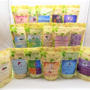 May include: A collection of 14 yellow pouches with floral designs, each containing bath salts. The pouches are labeled with the text "Luxury Bath Powder" and various scents, including "Coconut Milk", "Lavender", and "Rose Petals".