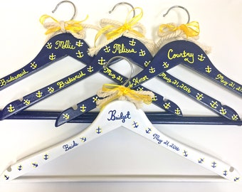May include: Navy blue and white wooden hangers with yellow anchor designs and names. Each hanger has a rope and yellow ribbon detail. Names include Mollie, Melissa, Courtney, and Bridget, with the date May 21, 2016.
