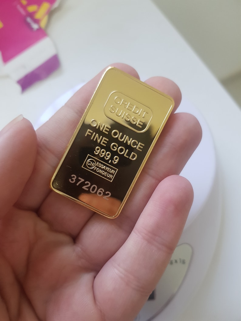 May include: A gold bar with the inscription "CREDIT SUISSE ONE OUNCE FINE GOLD 999.9 ESSAYEUR FONDEUR 372062"