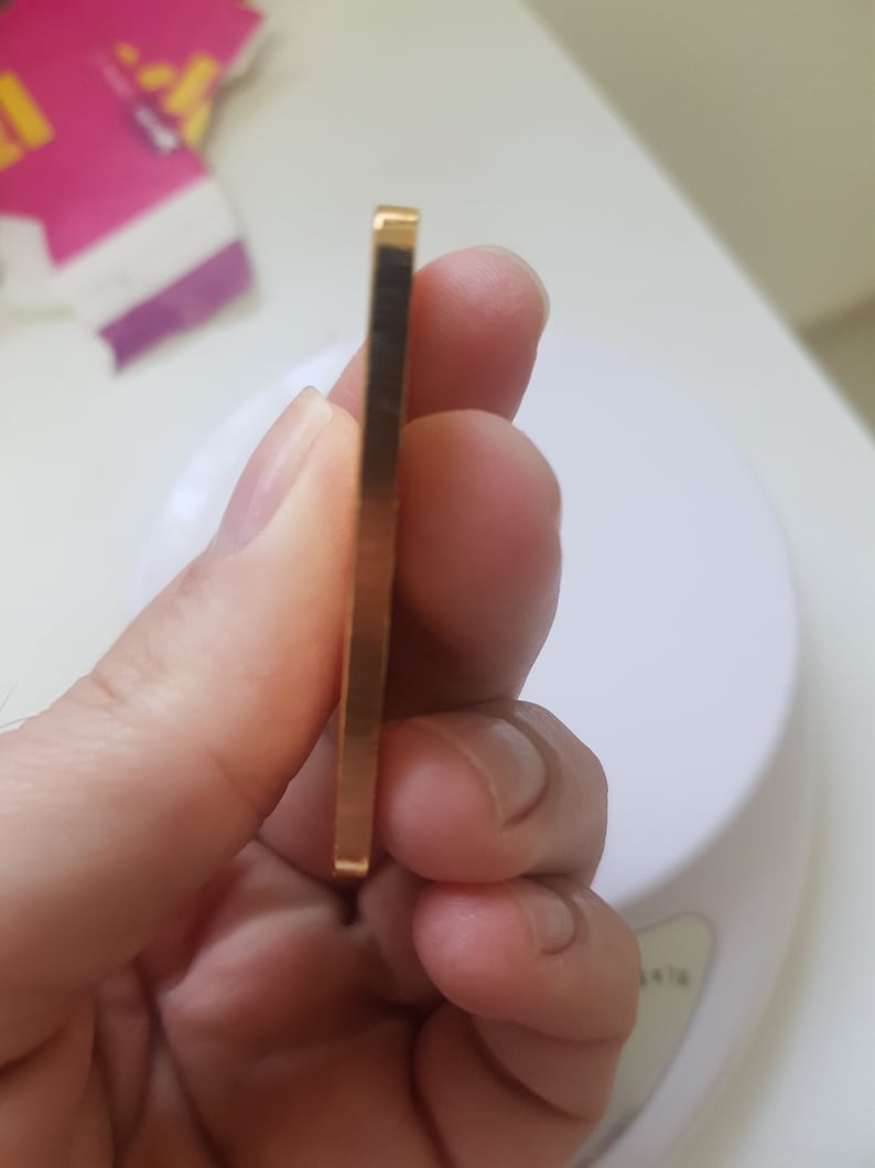 May include: A close-up of a gold bar, held in a hand. The bar is rectangular and has a smooth, shiny surface.
