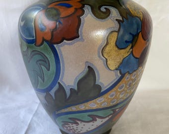 May include: A ceramic vase with a dark green glaze and a floral pattern in shades of blue, green, orange, and gold.