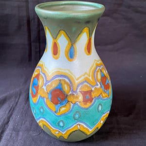 May include: A green, white, yellow, blue, and red ceramic vase with a geometric pattern.