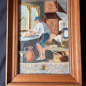 May include: A framed ceramic tile artwork depicting a historical scene with figures in a kitchen or bakery setting. The artwork features a brown wooden frame, a brown pitcher, and the text "1900" and "1950" with the word "Zeelandia".