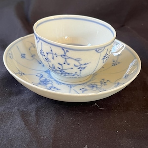 Puede incluir: Una taza de té y un platillo de porcelana blanca con un patrón floral azul y blanco. La taza y el platillo están decorados con un delicado diseño floral en azul y blanco.