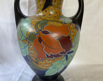 May include: A black ceramic vase with two handles and a floral design. The vase features a large orange flower with green leaves and yellow accents.