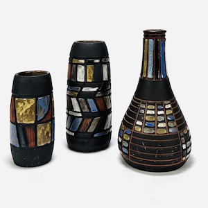 Pode incluir: Três vasos de cerâmica com padrões geométricos em tons de azul, amarelo, vermelho e marrom. Os vasos são todos pretos e têm um acabamento brilhante.