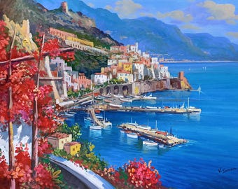 May include: An oil painting depicts a coastal Italian town with colorful buildings nestled along the shore. Red flowers frame the foreground, while boats dot the turquoise water. Mountains rise in the background under a bright blue sky.