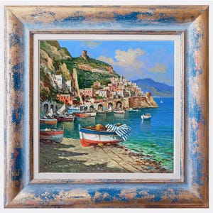 May include: Oil painting of a coastal town with boats in the water. The painting features a blue and white striped boat in the foreground, with a town on a hillside in the background. The painting is framed in a blue and gold distressed frame.