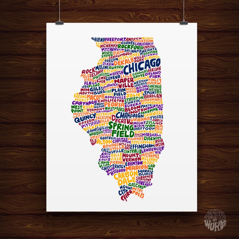 May include: A white poster with a colorful map of Illinois, USA, composed of city names. The state outline is filled with text in various colors, including Chicago, Springfield, and Peoria. The poster is hanging on a wooden wall.