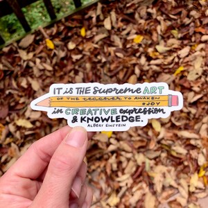 May include: A white sticker with a yellow pencil and text that reads "IT is THE Supreme ART OF THE teacher TO AWAKEN #JOY in CREATIVE expression & KNOWLEDGE. ALBERT EINSTEIN"