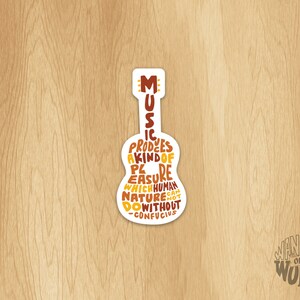May include: A white sticker with a guitar silhouette. The guitar is filled with text that reads "Music produces a kind of pleasure which human nature cannot do without -Confucius".