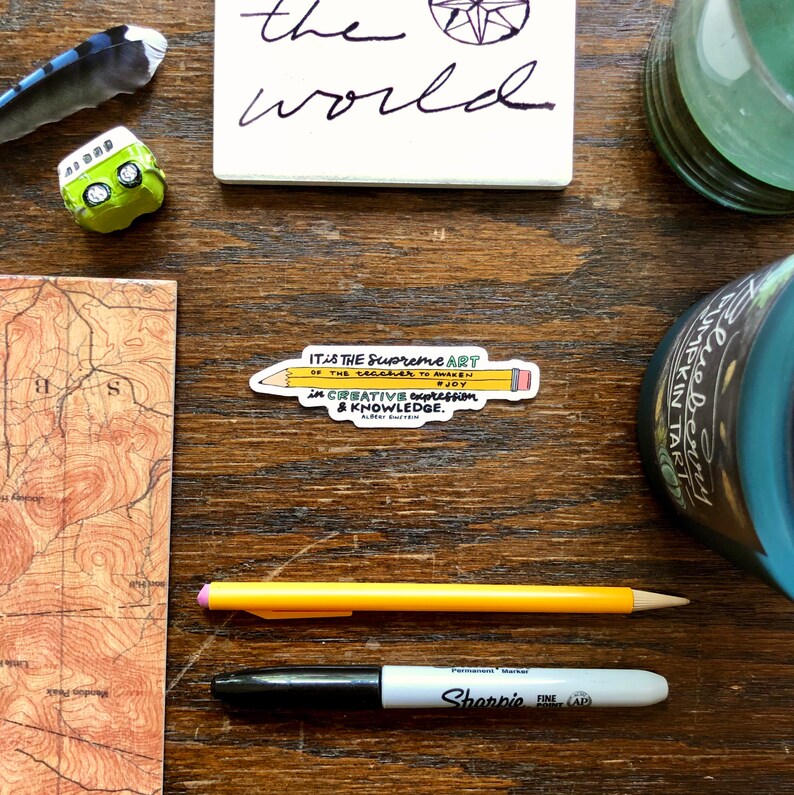 May include: A yellow pencil sticker with a quote about the supreme art of teaching. The quote reads "It is the supreme art of the teacher to awaken joy in creative expression & knowledge." - Albert Einstein