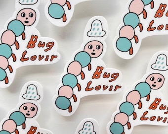 Peut inclure: Autocollants blancs avec un dessin de chenille de dessin animé. La chenille a un visage, des segments de corps bleus et roses et des pattes orange. Le texte "Bug Lover" est en écriture orange.