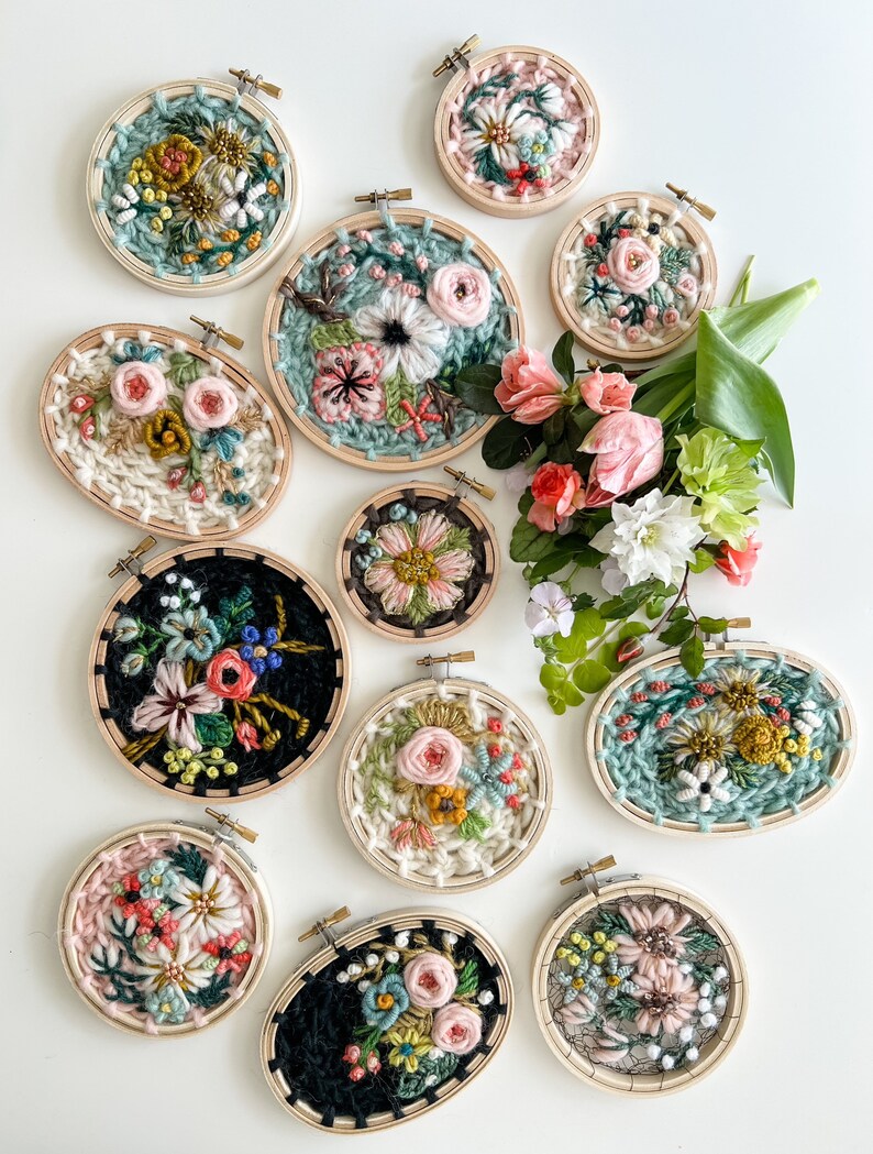 May include: A collection of 12 small embroidery hoops with floral designs. The hoops are made of wood and have a natural finish. The embroidery designs are colorful and feature a variety of flowers, leaves, and other botanical elements.