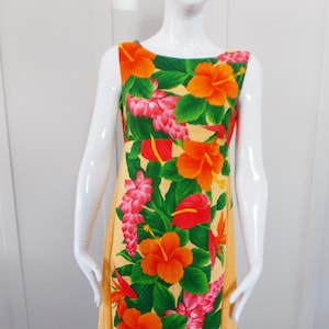 Puede incluir: Un vestido largo amarillo maxi con estampado tropical con flores naranjas, rojas y rosas sobre un fondo verde.