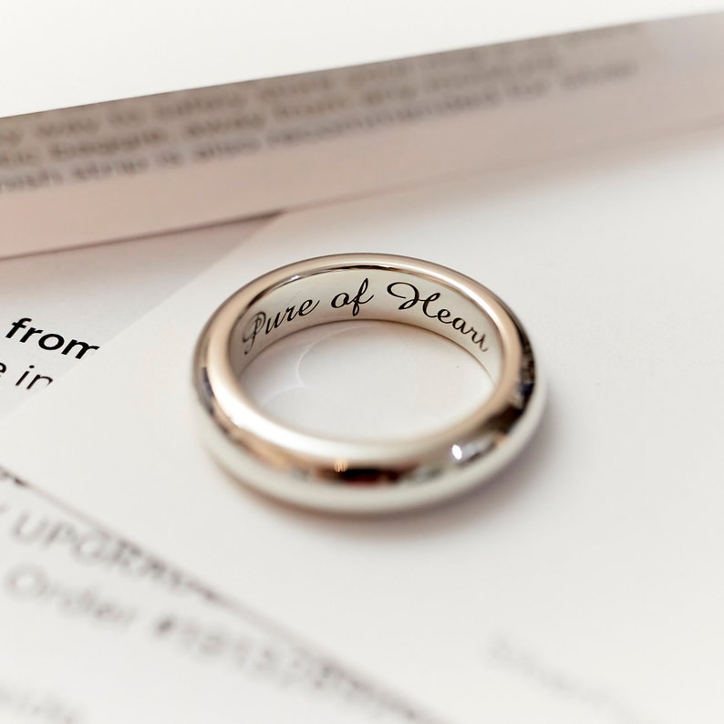 May include: A silver ring with the inscription "Pure of Heart" engraved on the inside.