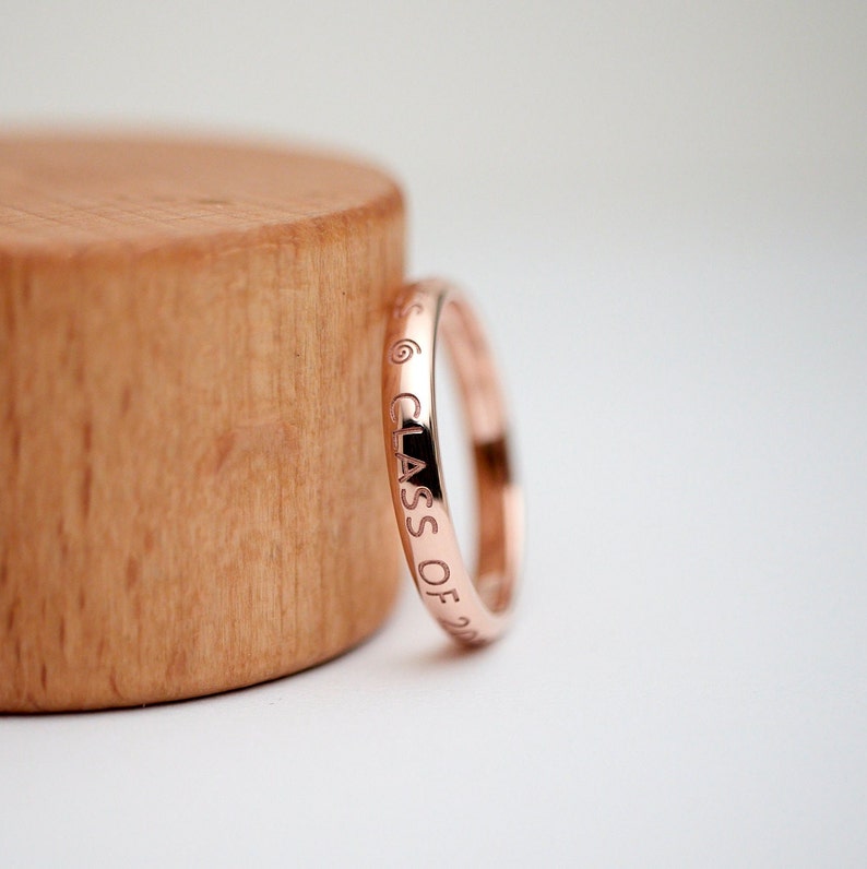 May include: A rose gold ring with the inscription "CLASS OF 20" engraved around the band.