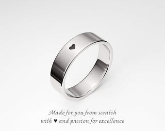 May include: A polished silver ring with a flat band and a small heart-shaped cutout. The ring is displayed on a white background. The text on the image reads: "Made for you from scratch with heart and passion for excellence."