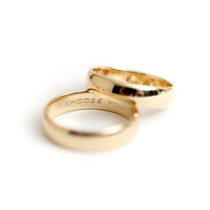 May include: Two gold wedding bands, one with the inscription "I CHOOSE YOU" on the inside.