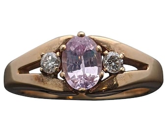 Può includere: Un anello d'oro con una pietra ovale rosa e due diamanti rotondi più piccoli su entrambi i lati.