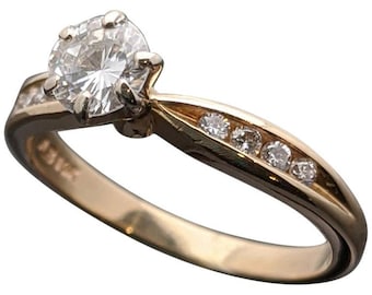 May include: A gold engagement ring with a single round diamond and smaller diamonds set in the band.