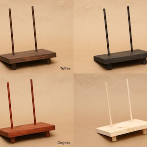 Pode incluir: Quatro suportes de exibi&ccedil;&atilde;o de madeira com diferentes acabamentos: Toffee, Preto, Conhaque e Sem Acabamento. Cada suporte tem duas cavilhas de madeira verticais e uma base retangular.