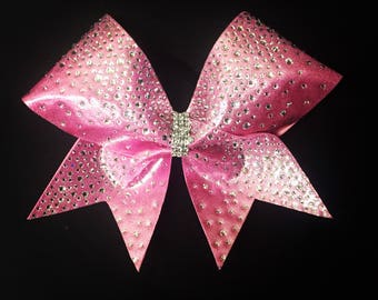 May include: A large pink cheer bow with silver glitter and rhinestones. The bow is tied with a silver ribbon.
