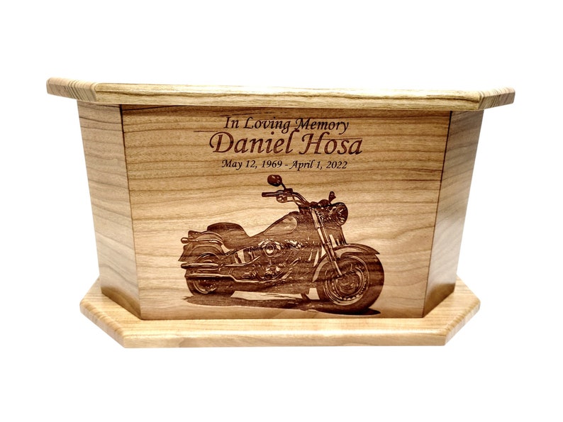 May include: Wooden cremation urn with an engraved image of a motorcycle and the text "In Loving Memory Daniel Hosa May 12, 1969 - April 1, 2022"