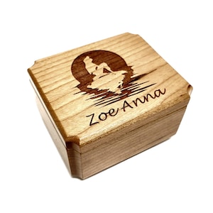 May include: A wooden music box with a laser engraved design of a mermaid sitting on a rock with waves in the background. The music box is personalised with the name "Zoe Anna".
