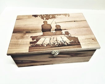 May include: A wooden box with a hinged lid and a brass latch. The lid features a laser-engraved design of two figures fishing under a tree.