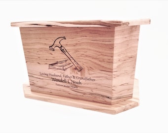 May include: A wooden box with a hammer and nail design engraved on the front. The box is inscribed with "Loving Husband, Father & Grandfather Wendell L. Noah Forever in our Hearts".