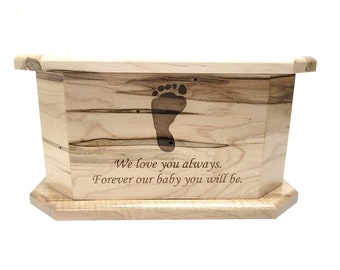 Puede incluir: Una caja de madera con un diseño de huella de pie y la inscripción "We love you always. Forever our baby you will be."