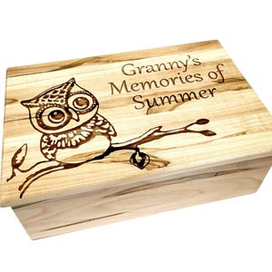 Peut inclure: Une boîte en bois avec un couvercle à charnière. Le couvercle est décoré d'un motif pyrogravé représentant un hibou perché sur une branche. Le texte "Granny's Memories of Summer" est également pyrogravé sur le couvercle.