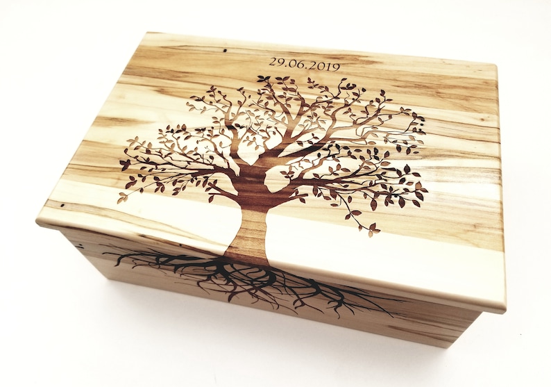 May include: A wooden box with a tree design carved into the lid. The tree has roots and branches with leaves. The date 29.06.2019 is engraved on the lid.