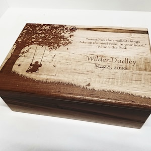 May include: A wooden box with a laser-engraved design of a child on a swing under a tree. The box has a quote from Winnie the Pooh and the name "Wilder-Dudley" with the date "May 8, 2020".