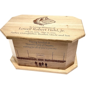 May include: A wooden box with an engraved image of a baseball glove and a baseball field. The box is inscribed with the words "In Loving Memory of Lowell Robert Hehl, Jr. July 26, 1969 - May 31, 2022 Father, Grandfather, Brother, Uncle and Son Playing baseball in Heaven's Field of Dreams, waiting for all of you to join me."