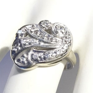 May include: A silver ring with a detailed design of a stylized flower with small diamonds set in the metal.