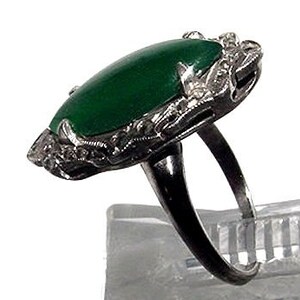 May include: A vintage ring with a large, oval-shaped green jade stone set in a delicate silver filigree design.